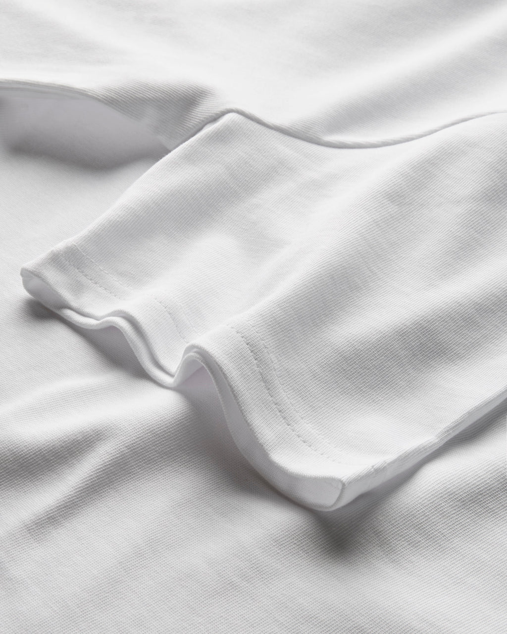 Close-up of heavyweight white T-shirt fabric showing the hem and stitching