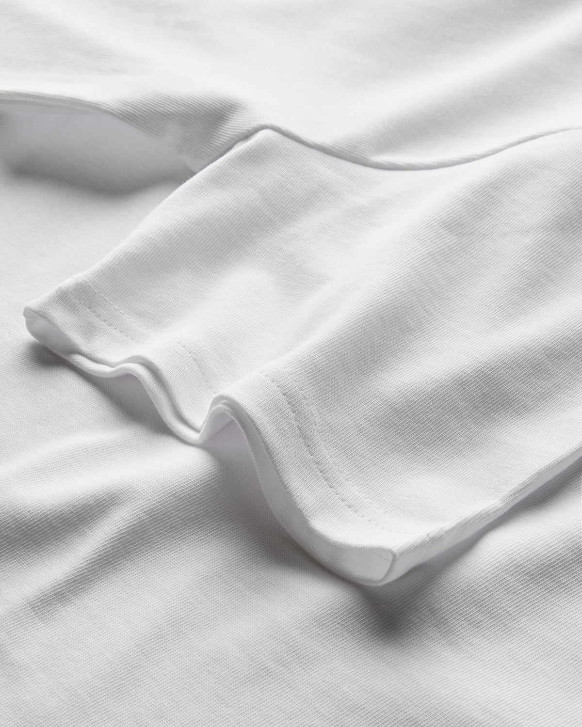 Close-up of heavyweight white T-shirt fabric showing the hem and stitching