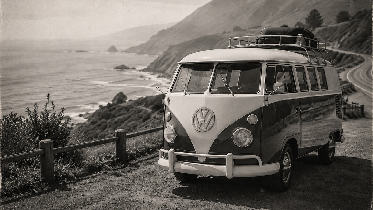 Vintage black and white VW T1 campervan parked beside a winding coastal road, representing freedom, exploration and life on the road.