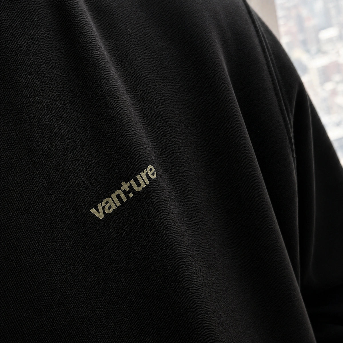 Close-up of the black Vanture Beginning Hoodie showing the Vanture chest print