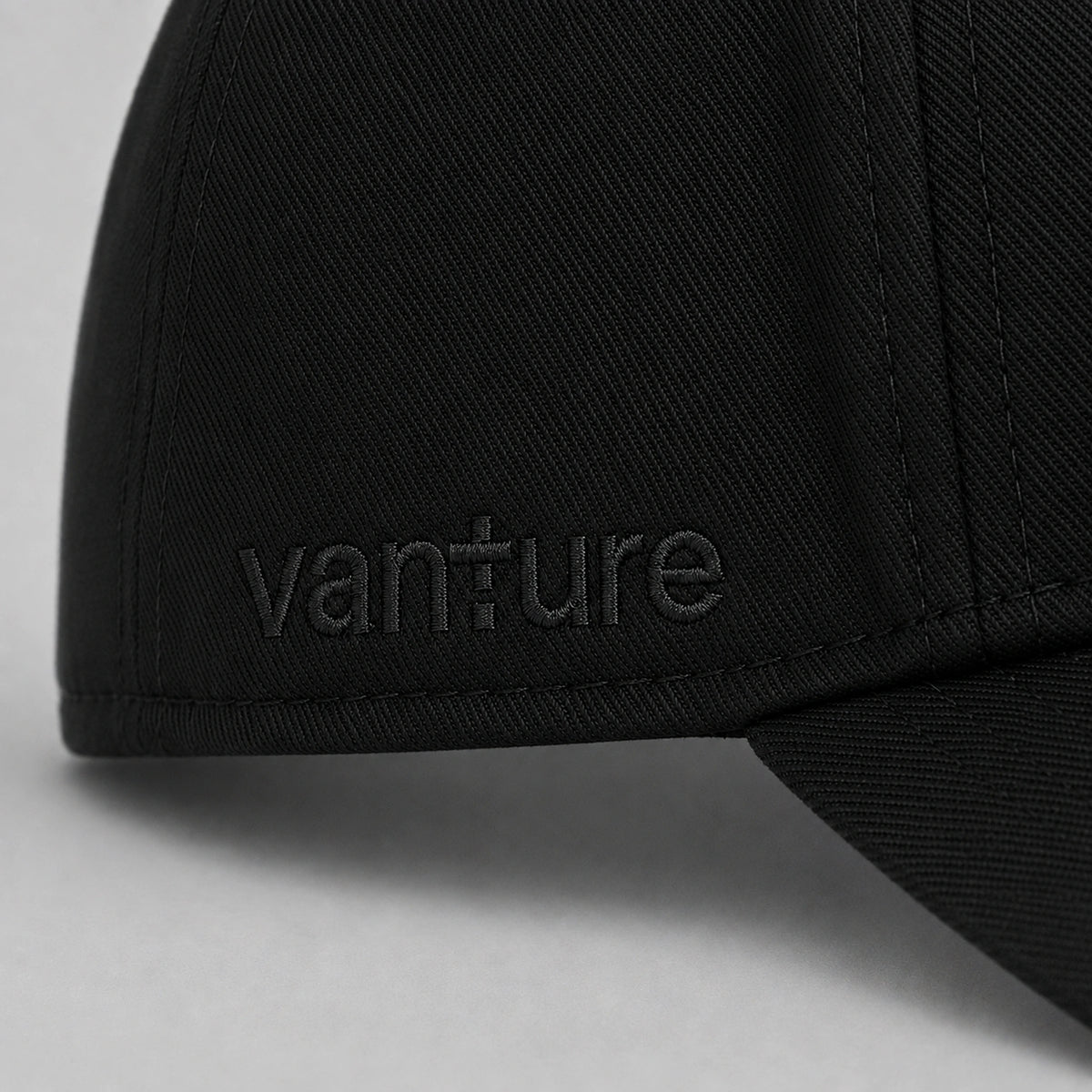 Close-up of black Vanture Icon Cap showing tonal Vanture embroidery and fabric texture