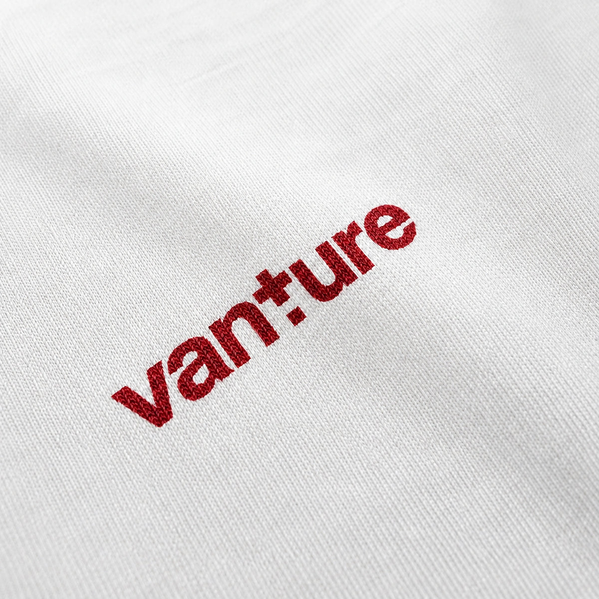 Close-up of the Vanture T1 Era T-shirt logo printed in Sealing Wax Red on white fabric
