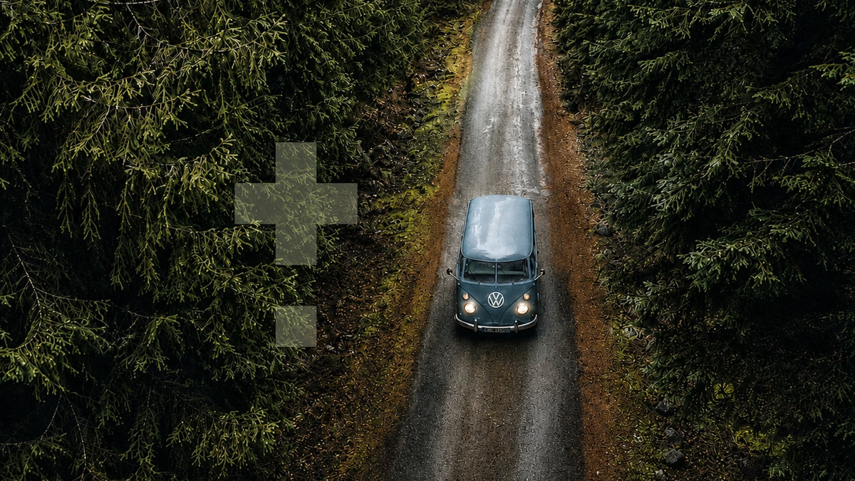 Vintage Volkswagen T1 campervan driving along a narrow forest road