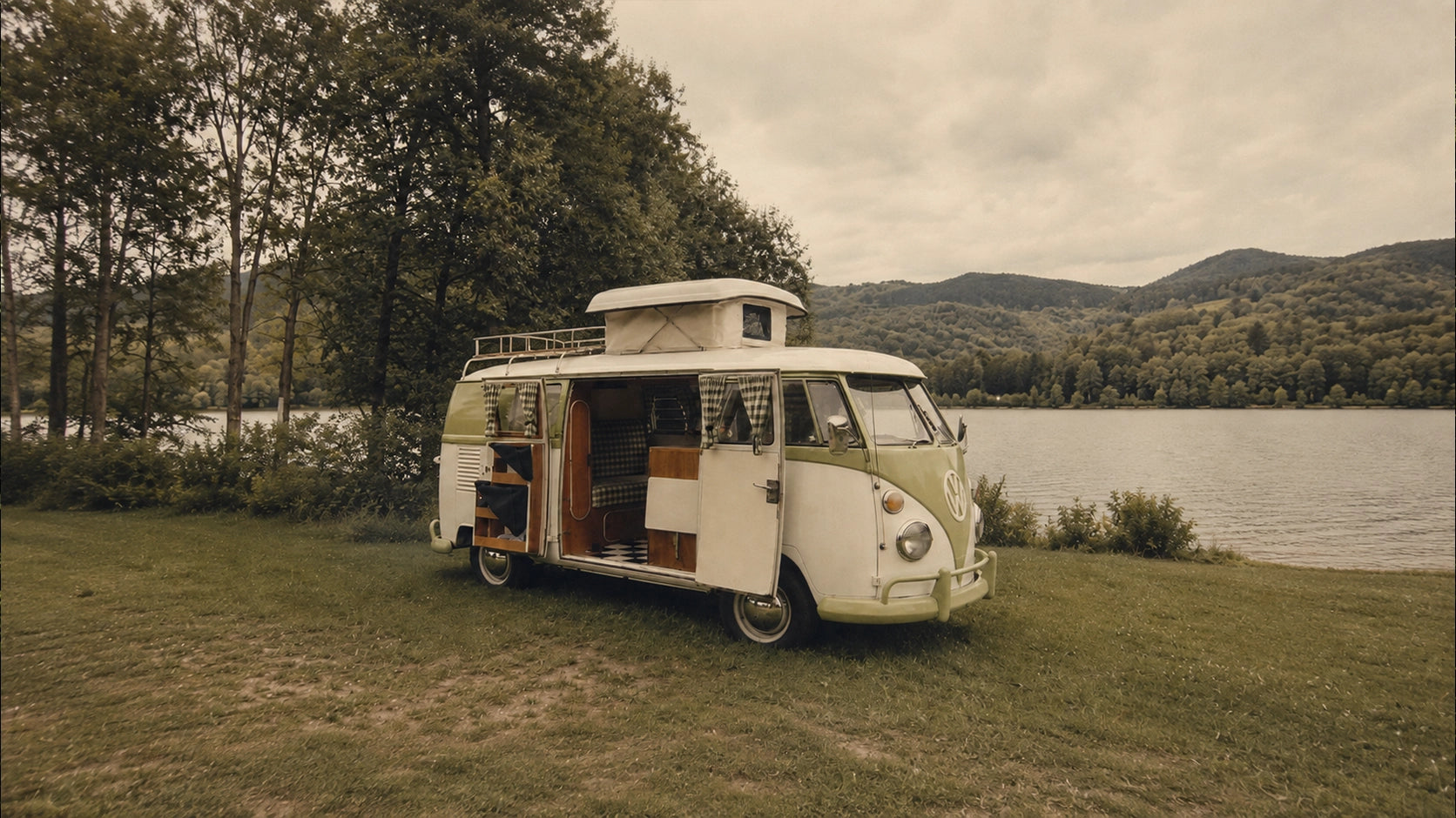 Vintage Volkswagen T1 pop-top campervan parked beside a lake