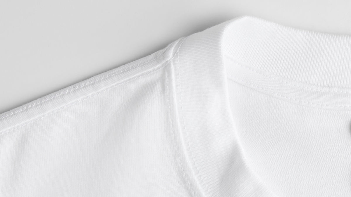 Close-up detail of black heavyweight cotton T-shirt fabric showing the ribbed collar and material texture.
