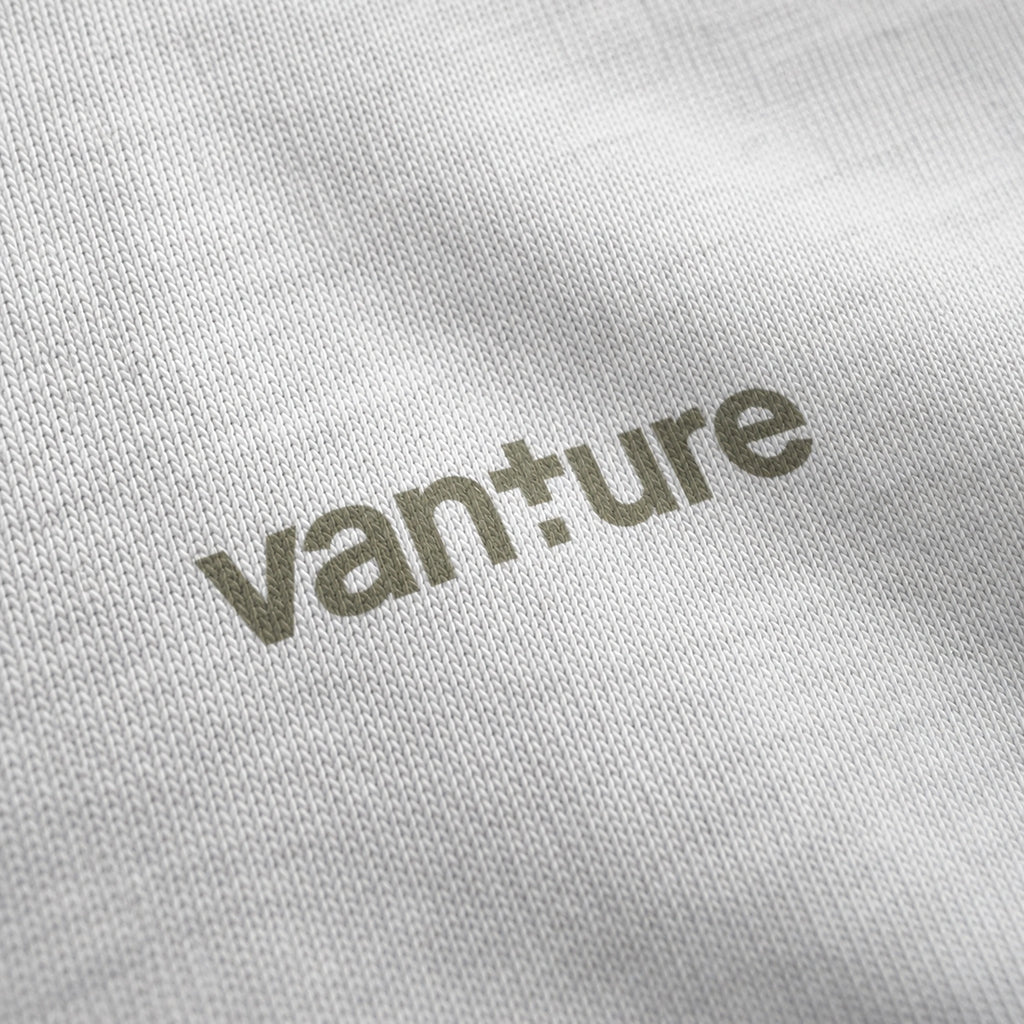 Close-up of the white Vanture Your Journey T-shirt chest logo printed in muted olive on white cotton fabric