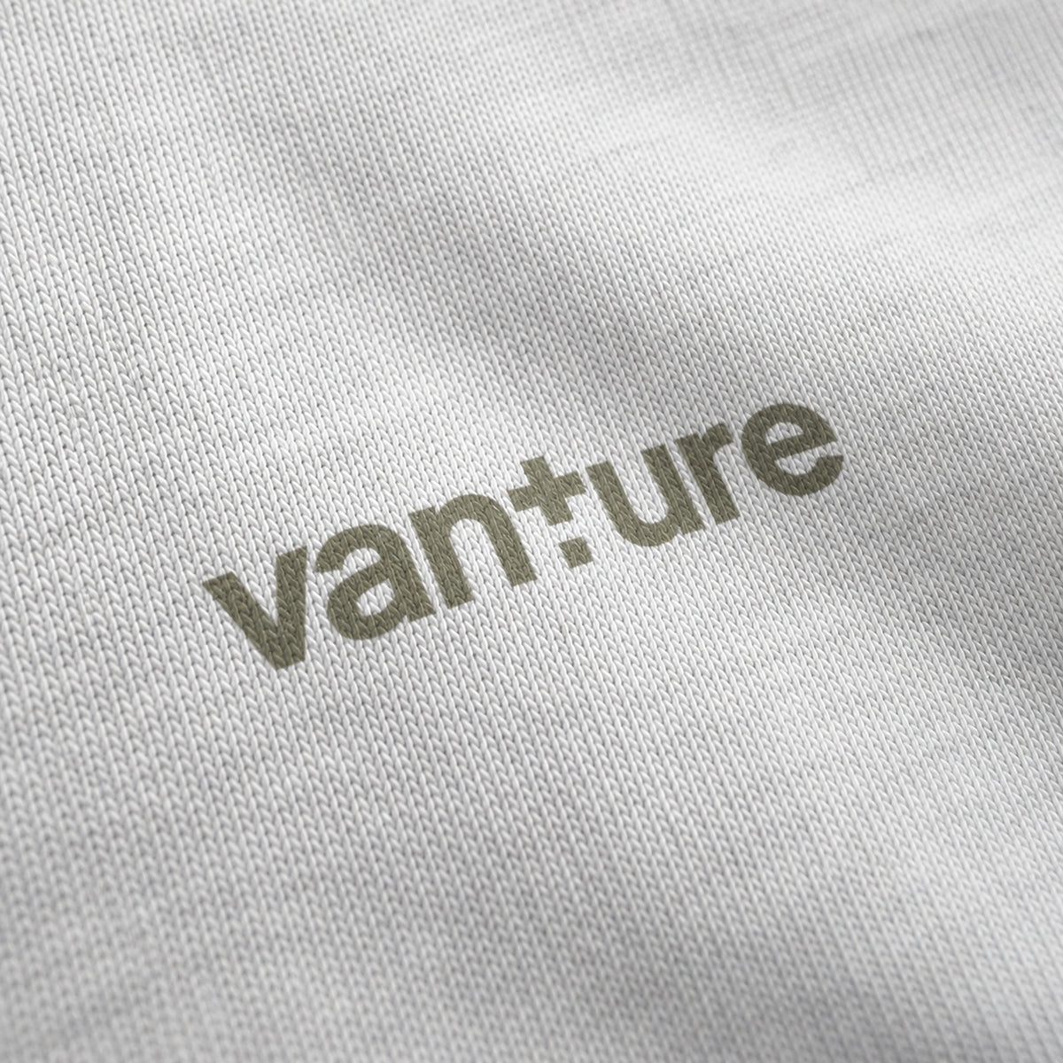 Close-up of the white Vanture Your Journey T-shirt chest logo printed in muted olive on white cotton fabric